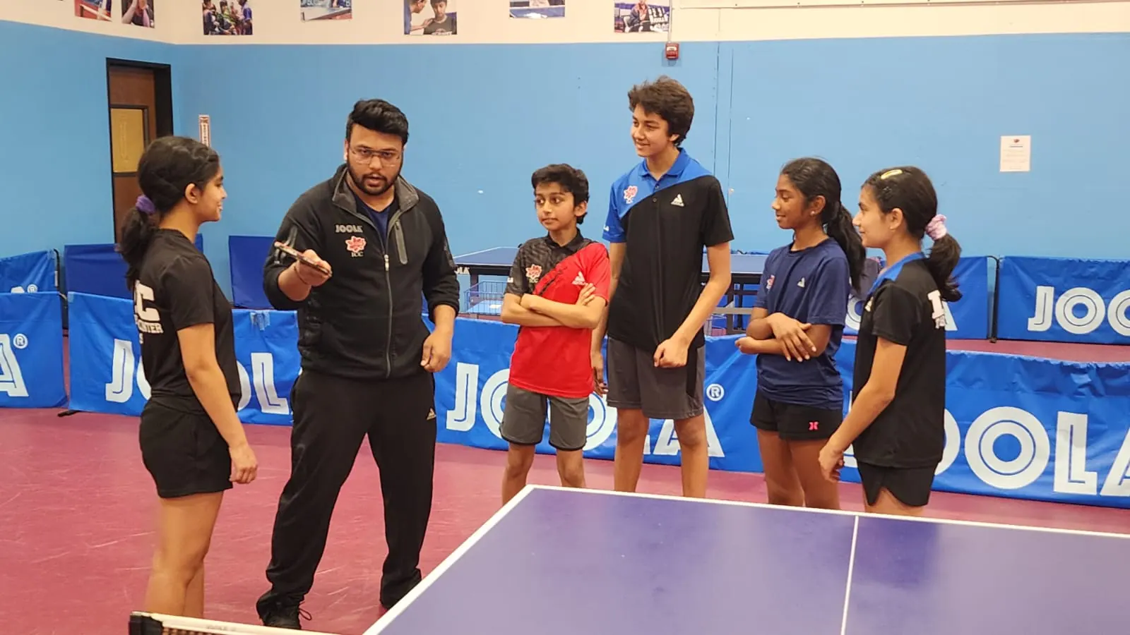 Subham Kundu briefing six young players beside a table at ICC Table Tennis Center