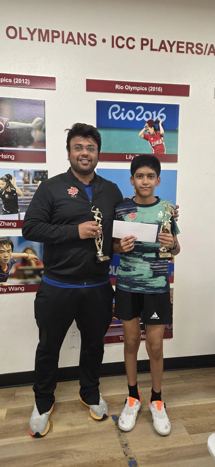 Shreyan Modak holding a trophy and certificate beside Subham Kundu at the ICC Table Tennis Center